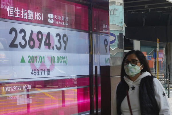 홍콩 시내에 있는 은행에 설치된 주가지수 전광판 앞을 마스크를 착용한 주민이 지나가고 있다./뉴시스